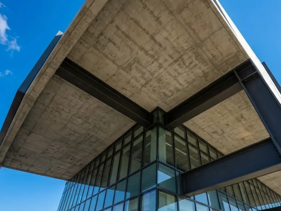 Looking up at a concrete canopy over a glass entrance