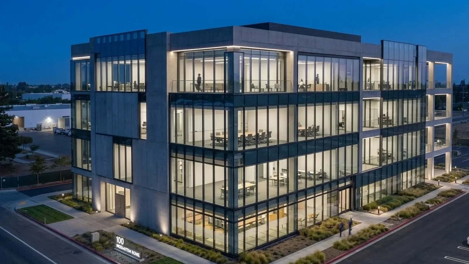 A glass-fronted commercial building lit at dusk