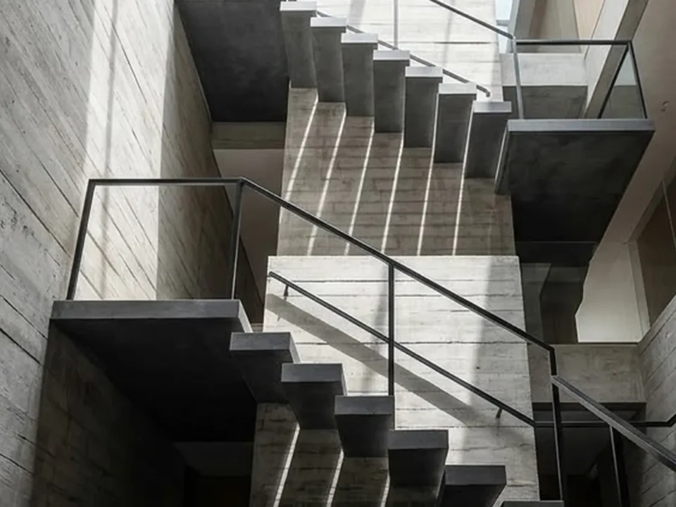 A concrete stair core rising through a modern building, lit from above