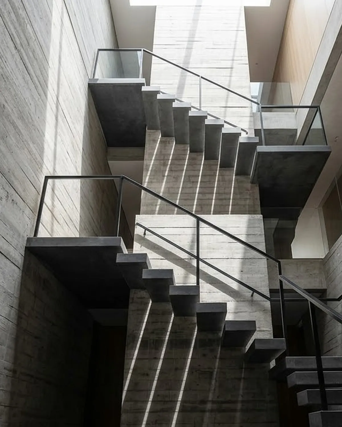 A concrete stair core rising through a modern building, lit from above